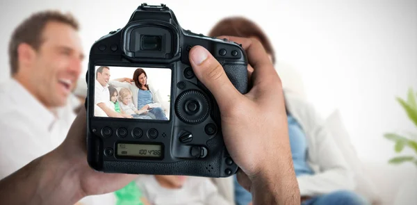 Manos sosteniendo la cámara con familia feliz en la pantalla —  Fotos de Stock