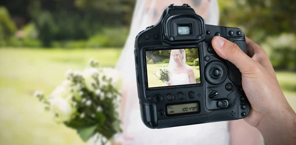 Abgeschnittene Hand eines Fotografen, der Kamera gegen wegschauende Braut hält — Stockfoto