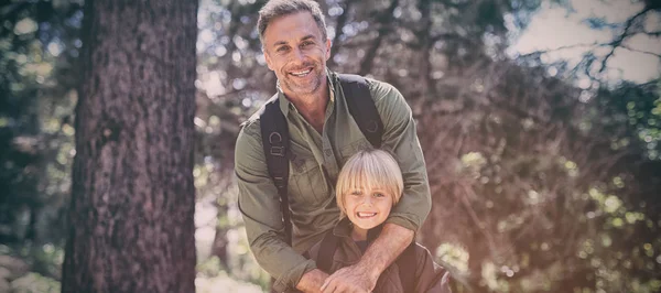 Gelukkig vader en zoon permanent tegen bomen in bos — Stockfoto