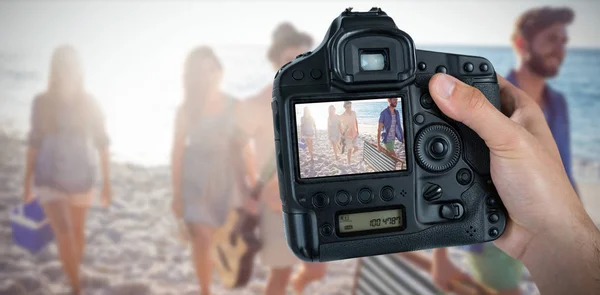 Fotografo che tiene la fotocamera con gli amici sulla spiaggia sullo schermo — Foto Stock