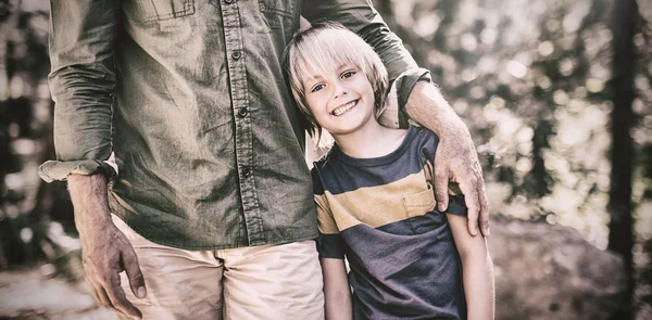 Lachende jongen permanent met vader op zonnige dag in het bos — Stockfoto