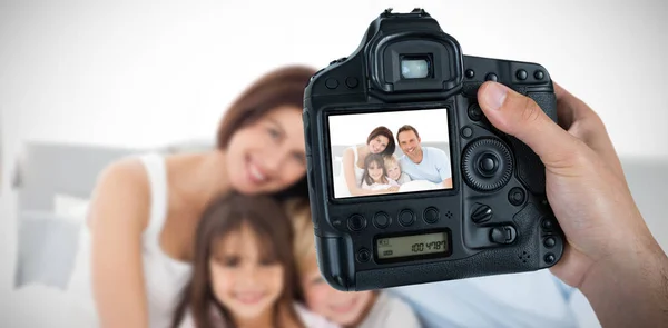Mani che tengono la fotocamera con la famiglia felice sullo schermo — Foto Stock