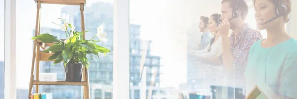 Asistentes de servicio al cliente con auriculares con fondo de oficina brillante — Foto de Stock