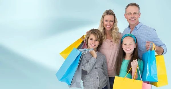 Family with shopping bags against blurry blue abstract background — Stock Photo, Image