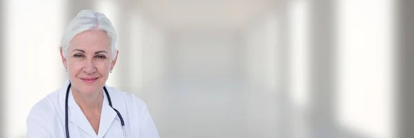 Médico sorrindo contra o corredor branco borrado — Fotografia de Stock
