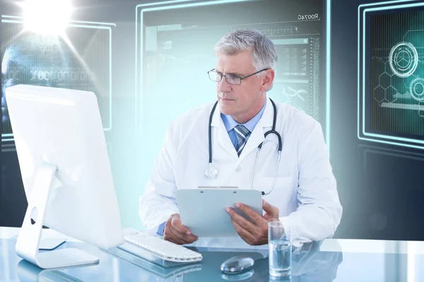 Mannelijke arts Klembord te houden terwijl het computerscherm kijken — Stockfoto