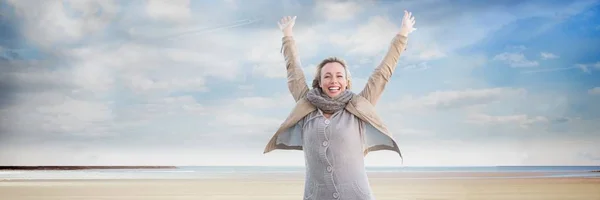 Vrouw in jas en sjaal vieren op strand met vliegtuig in de lucht — Stockfoto