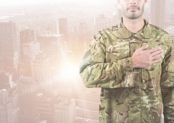 Militär med hand på sitt hjärta mot en stad — Stockfoto