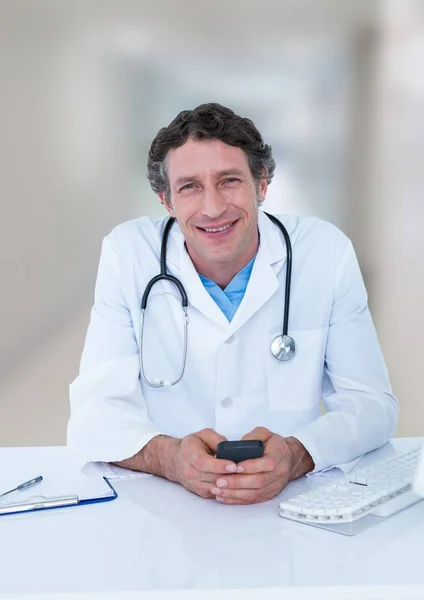 Dokter di meja dengan telepon terhadap lorong kabur — Stok Foto