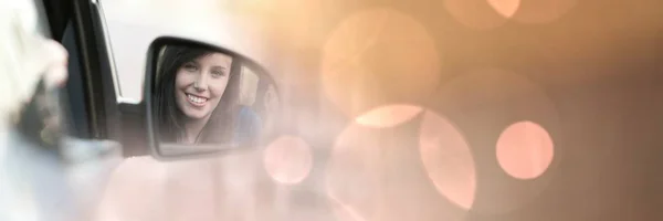 Женщина смотрит в зеркало автомобиля с мечтательными огнями bokeh переход — стоковое фото