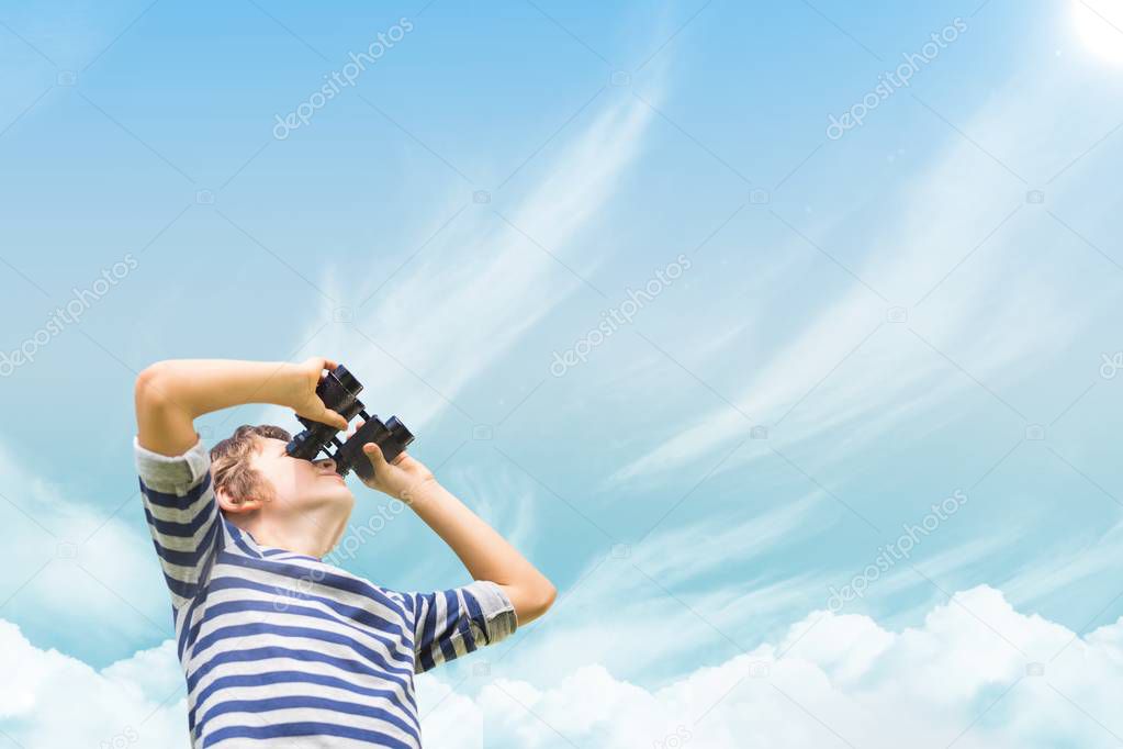 Boy looking through binoculars against sky