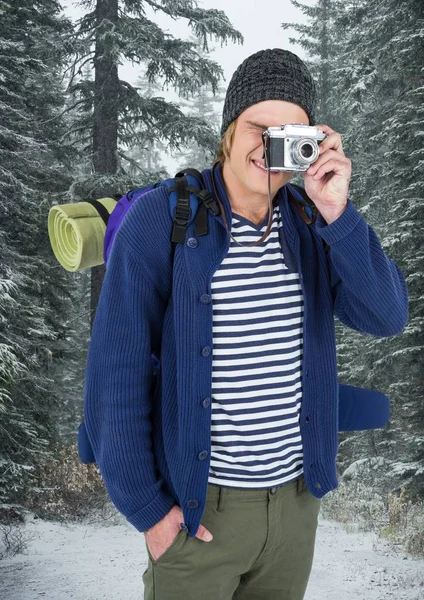 Tysiąclecia backpacker aparatem przeciwko ośnieżonych drzew — Zdjęcie stockowe