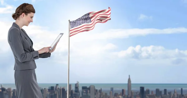 Geschäftsfrau auf Tablet mit amerikanischer Flagge im Stadtbild — Stockfoto