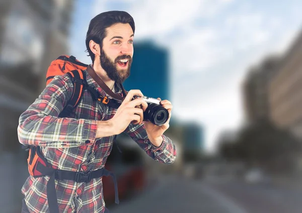 Duizendjarige backpacker met camera tegen wazig straat — Stockfoto