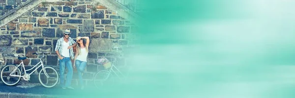 Couple with bikes against brick wall and blurry green transition — Stock Photo, Image