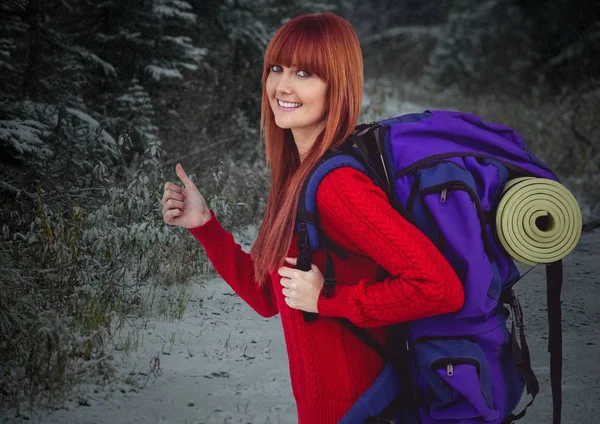 Millennial Backpacker Daumen hoch gegen verschneiten Wald — Stockfoto