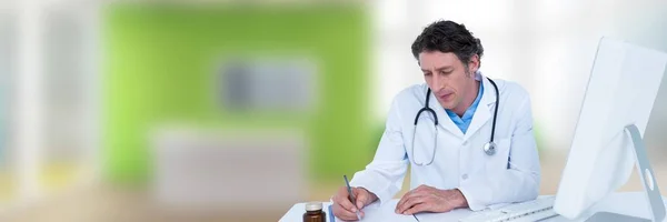 Médico escrevendo na mesa contra escritório borrado verde — Fotografia de Stock