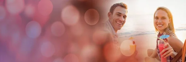 Millennial couples having cocktails on beach with red bokeh transition — Stock Photo, Image