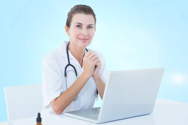 Imagen compuesta 3d del médico femenino seguro con el ordenador portátil en la mesa —  Fotos de Stock