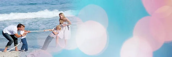 Familie spelen Touwtrekken op strand met blauwe en roze bokeh overgang — Stockfoto