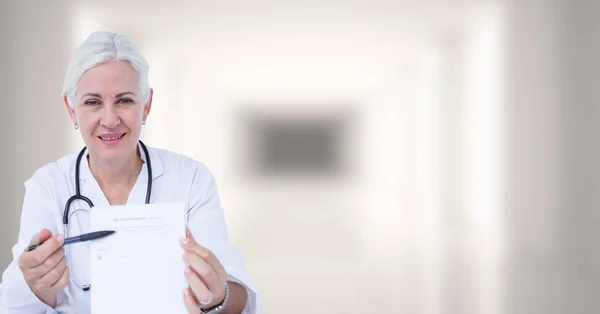 Médico segurando prancheta contra corredor branco embaçado — Fotografia de Stock