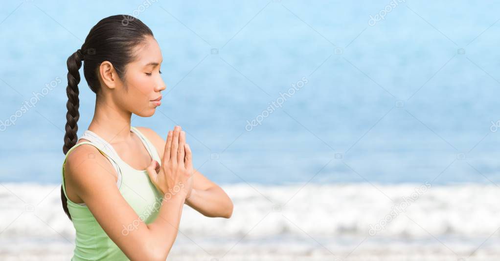 Woman meditating against blurry water