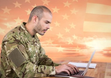 Amerikan bayrağı önünde bir dizüstü bilgisayar kullanarak asker