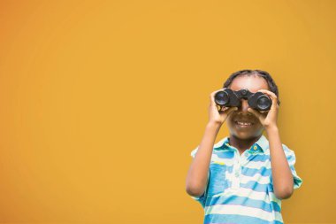 Dürbün sarı arka plana karşı bakarak mutlu çocuk