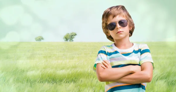 Pojke med solglasögon armar viks mot äng — Stockfoto
