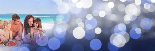 Family at beach with bucket and spade with blue bokeh transition — Stock Photo, Image