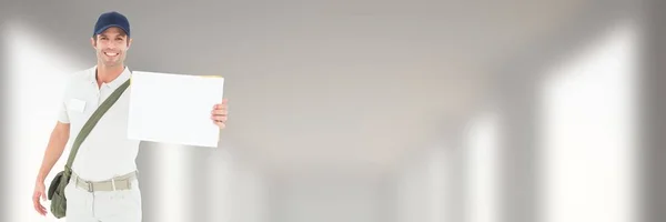 Entrega Mensajero sosteniendo un cartel en blanco frente a un fondo borroso — Foto de Stock
