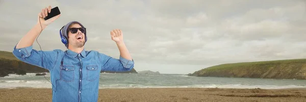 Homem milenar em fones de ouvido dançando na praia nublada — Fotografia de Stock