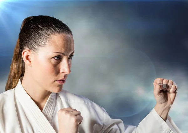 Kvinna i karate kostym poserar mot moln och nödraketer — Stockfoto