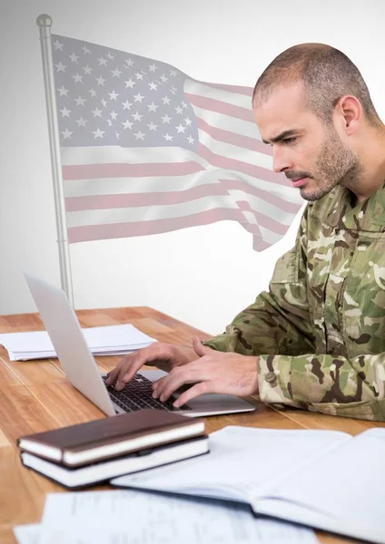 Militar trabalhando em seu laptop contra bandeira americana — Fotografia de Stock