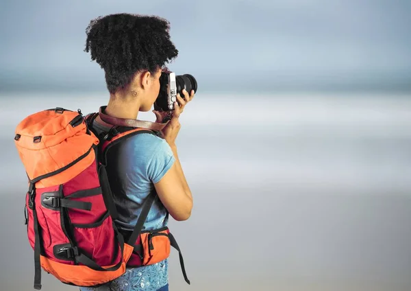 Χιλιετή backpacker με κάμερα ενάντια θολή παραλία — Φωτογραφία Αρχείου