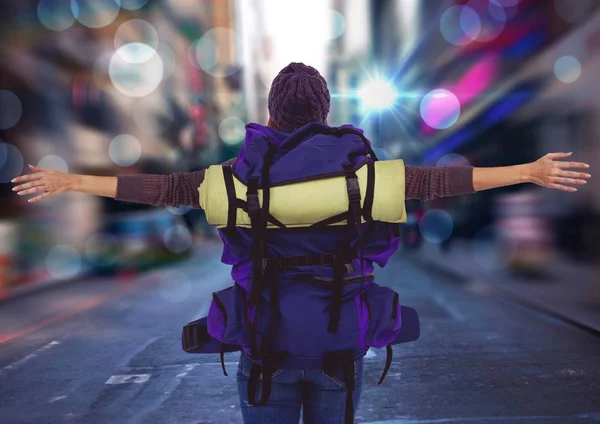 Baksidan av tusenåriga backpacker armarna utsträckta mot suddiga street — Stockfoto