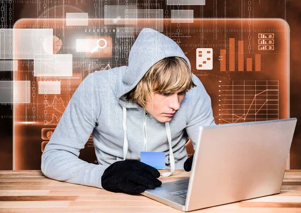 Hacker met behulp van een laptop en houden van een credit card — Stockfoto