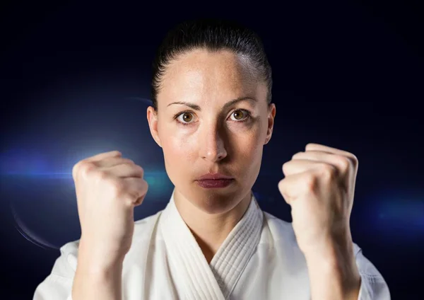 Kvinna i karate passa mot blå flare — Stockfoto