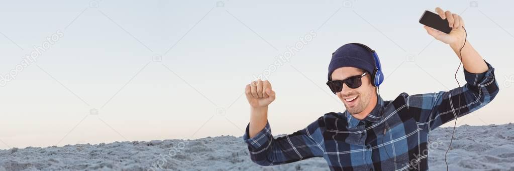 Millennial man with headphones dancing against sand and evening sky 3d