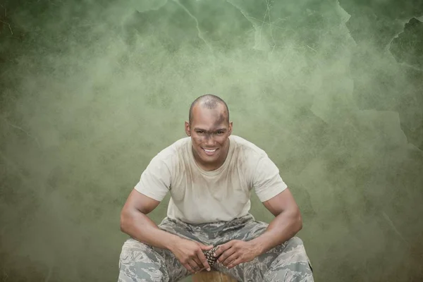 Gelukkig soldaat man zit tegen een groene achtergrond — Stockfoto