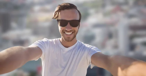 Hombre tomando selfie contra ciudad borrosa — Foto de Stock