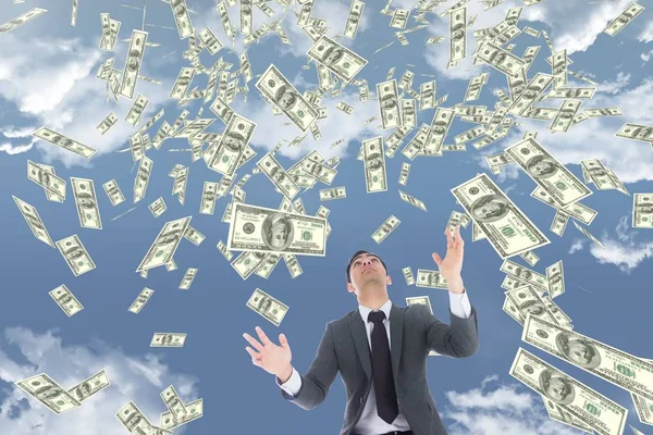 Homem de negócios olhando para o dinheiro chuva contra céu com nuvens — Fotografia de Stock