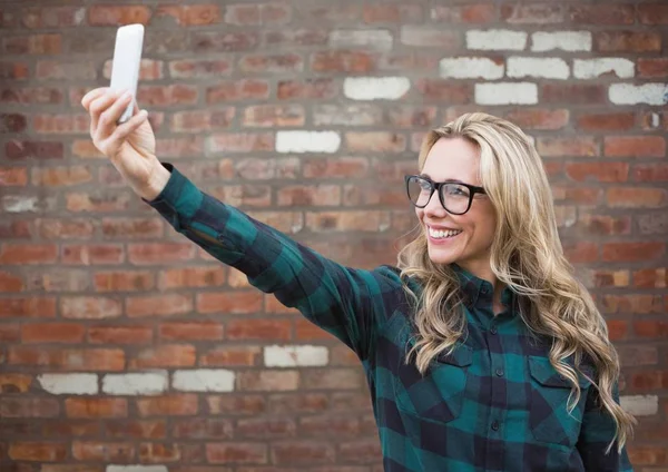 Femme millénaire prenant selfie contre mur de briques rouges — Photo