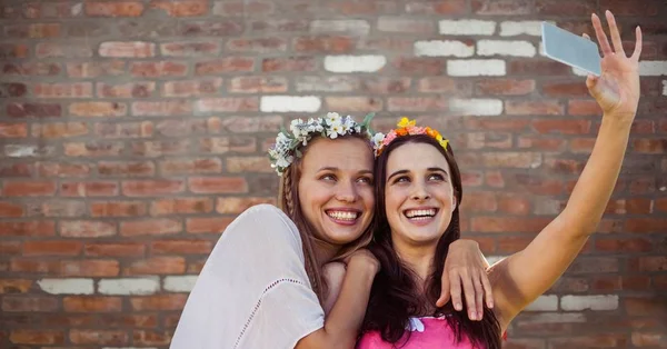 Hippie tjejer tar selfie mot röd tegelvägg — Stockfoto