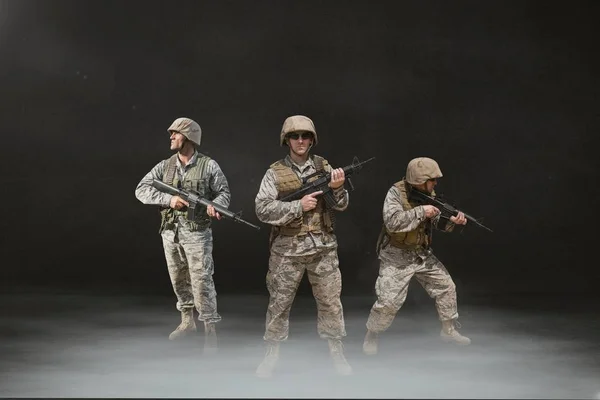 Soldaat mannen houden van wapens tegen zwarte achtergrond — Stockfoto