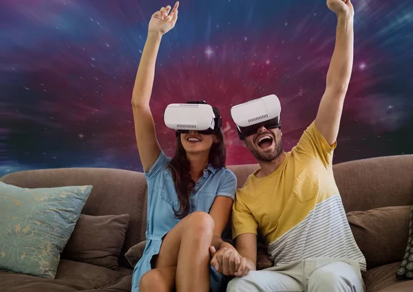 Casal animado no fone de ouvido VR sentado contra fundo galáxia — Fotografia de Stock
