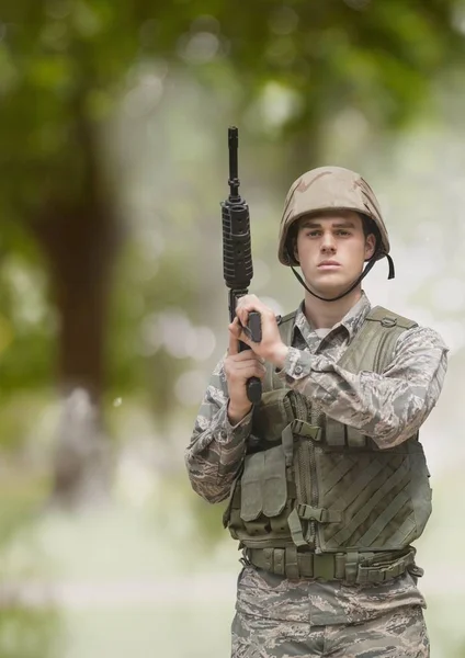 Στρατιώτης άνθρωπος που κρατά ένα όπλο ενάντια σε πράσινο φόντο με καπνό — Φωτογραφία Αρχείου