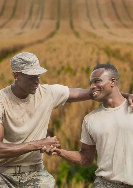 Gelukkig soldaat mannen geven handen tegen de achtergrond van een veld — Stockfoto