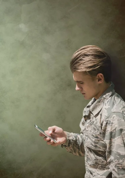 Στρατιώτης ο άνθρωπος βλέπει ένα τηλέφωνο ενάντια σε πράσινο φόντο — Φωτογραφία Αρχείου