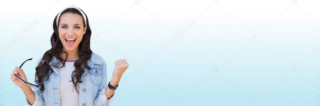 Millennial woman celebrating against blurry blue and white background